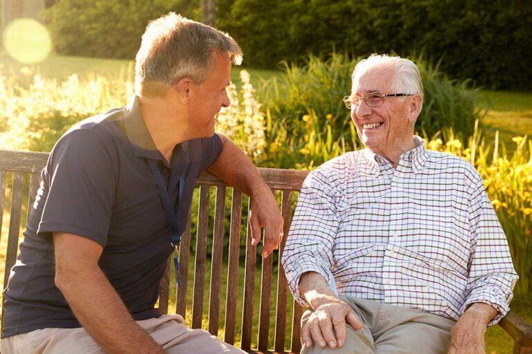 A caregiver helps an older adult review a daily schedule together at a kitchen table.